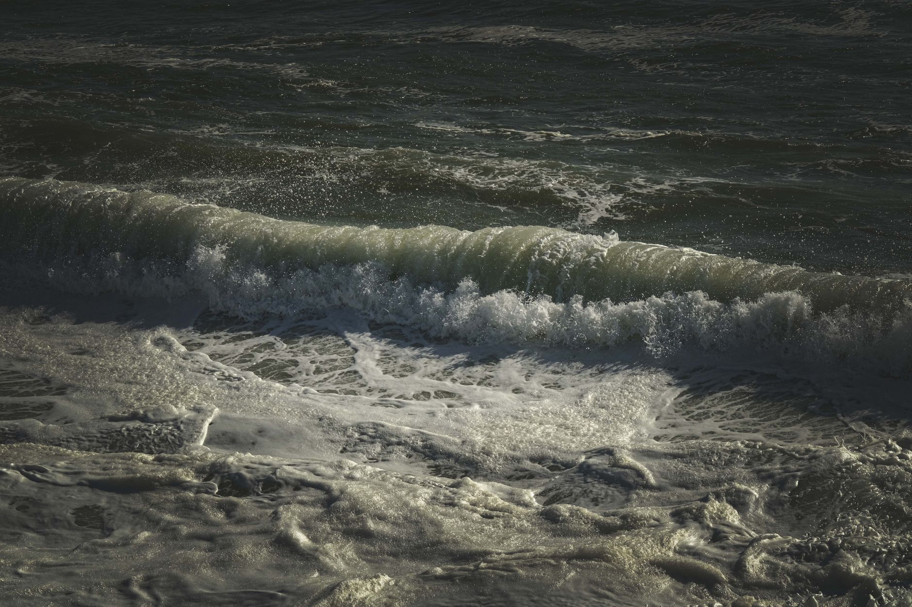 Dark ocean waves with white foam creating dynamic seascape.