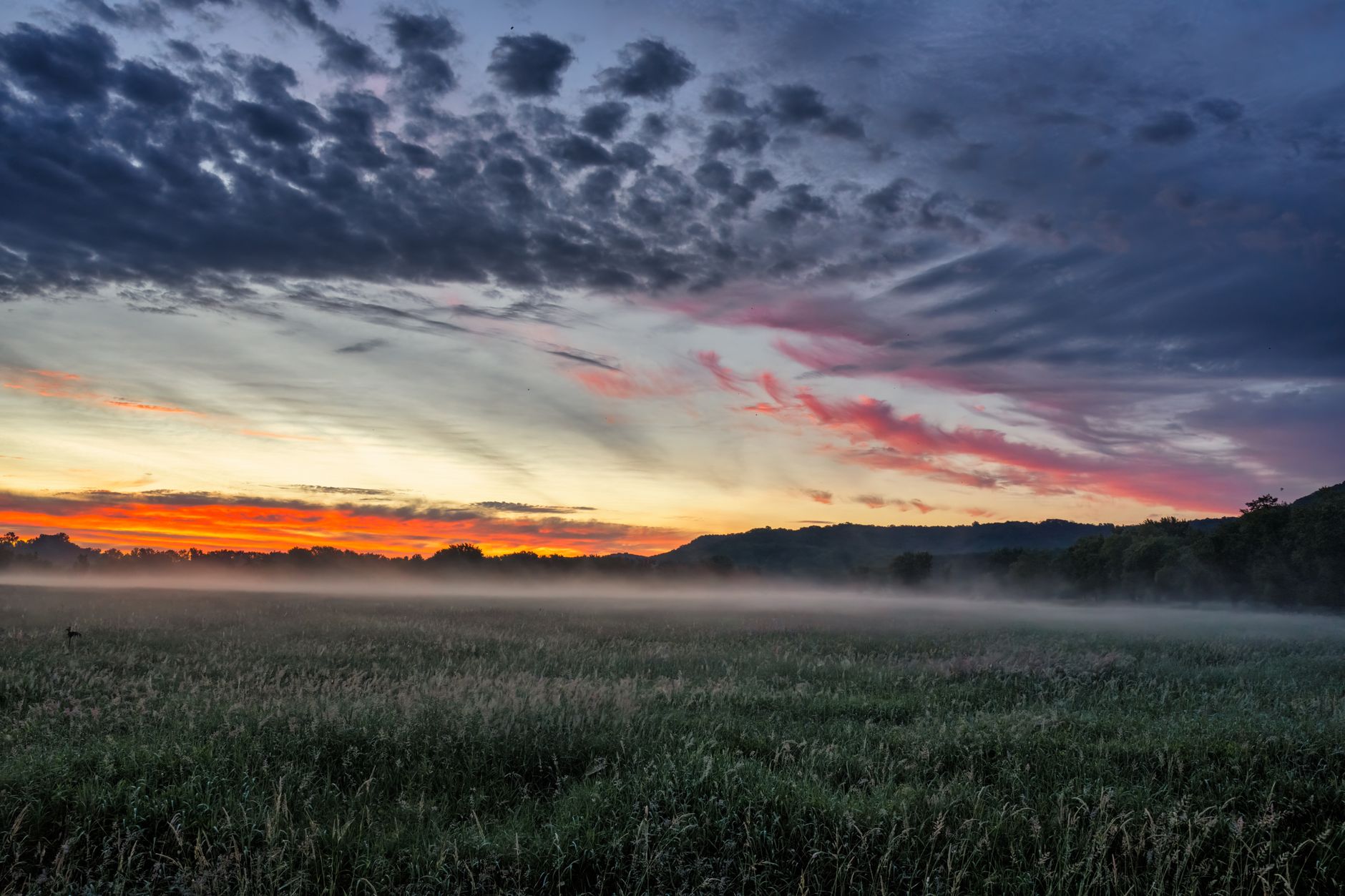 A breathtaking sunset casts vivid colors over a misty field in Modena, Wisconsin, creating a serene rural land