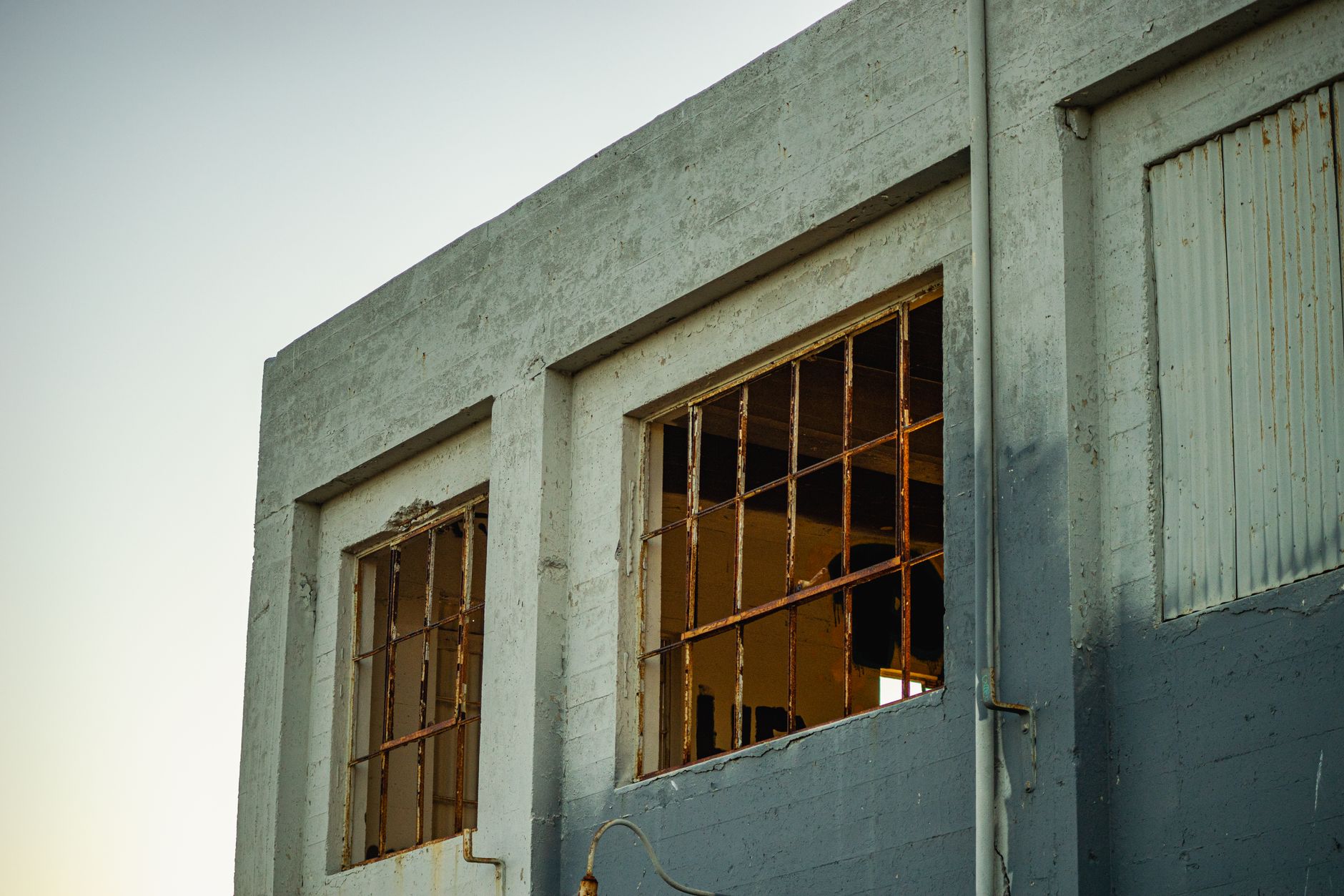 An exterior view of a weathered, abandoned industrial building with broken windows.
