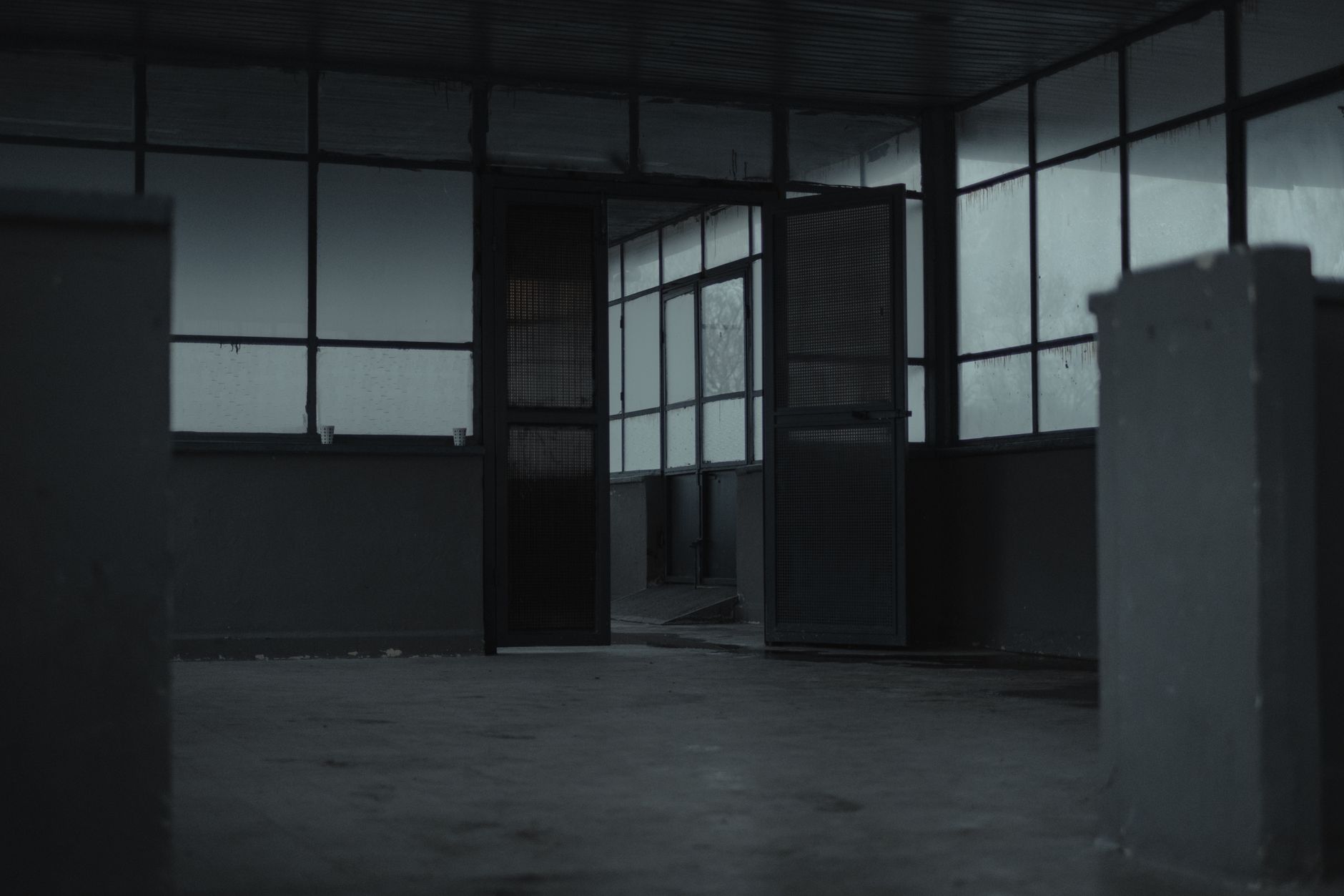 Interior of spacious empty room of gloomy abandoned building with glass windows and opened door